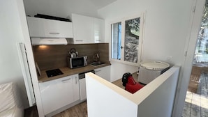 A compact kitchen with white cabinets, a microwave, a kettle, and a sink. - 148 – Charming House with Large Garden – Ideal for 4 to 6 Guests ?? (SOULAC SUR MER)