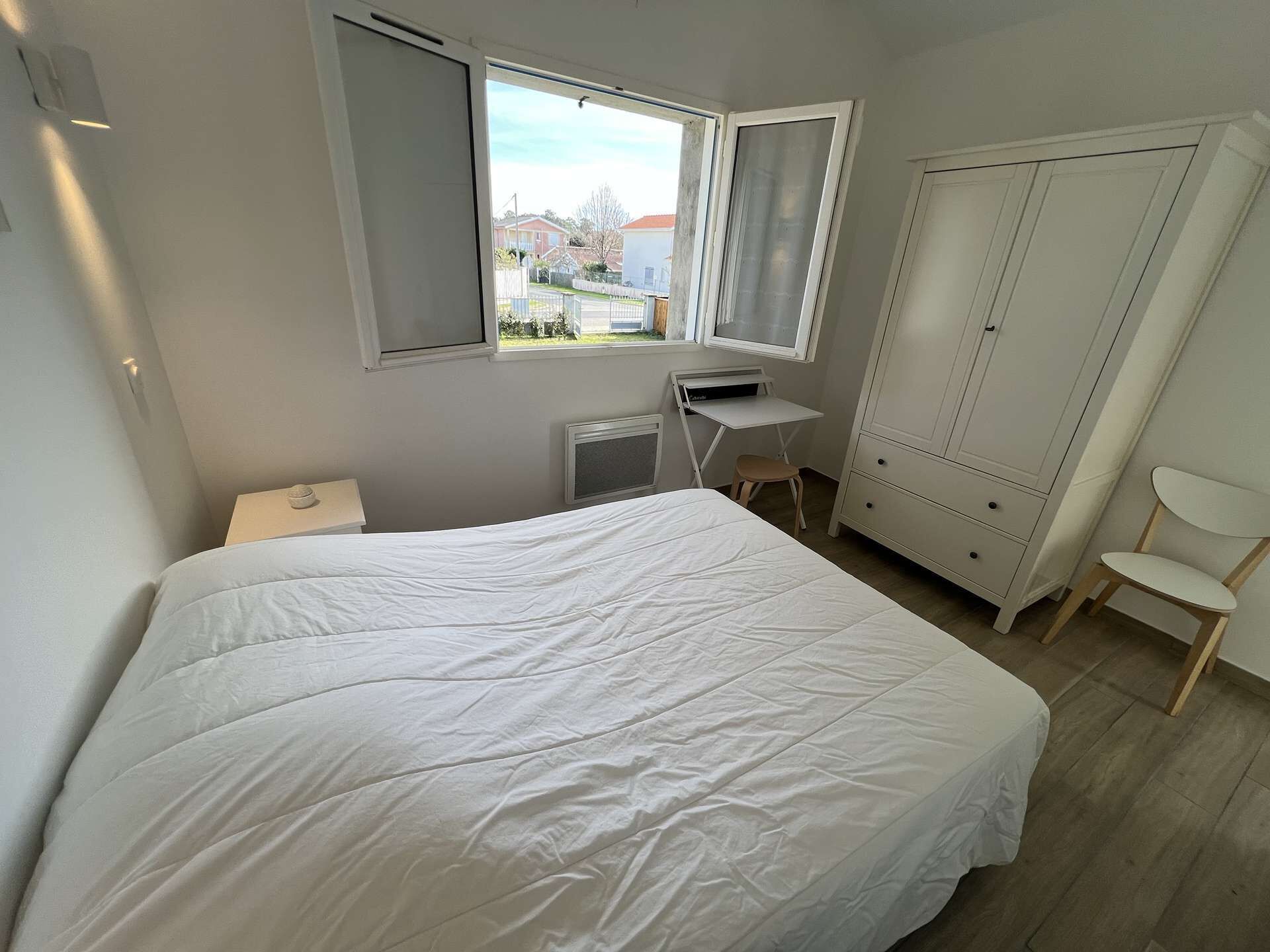 Ein Schlafzimmer mit Bett, Schreibtisch, Stuhl und Kleiderschrank.