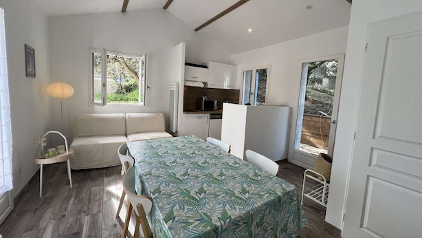 A compact, well-lit room with a dining table, a sofa, and a kitchenette. - 148 – Charming House with Large Garden – Ideal for 4 to 6 Guests ?? (SOULAC SUR MER)