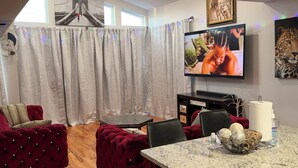 A living room with a TV, red velvet sofas, a dining table with a paper towel dispenser, and a decorative bowl. - Cozy 3-bedroom house in perfect Newark with cool AC/HEAT and comfort (Newark)