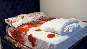 A bed with a floral bedspread, a white pillow, and a blue headboard. - Cozy 3-bedroom house in perfect Newark with cool AC/HEAT and comfort (Newark)