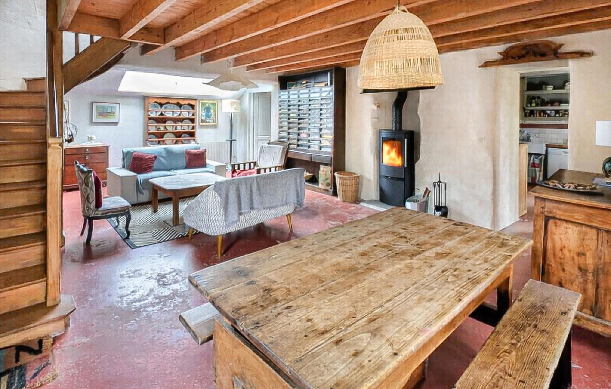 Un interior rústico con una mesa de comedor de madera, un sofá y una chimenea.