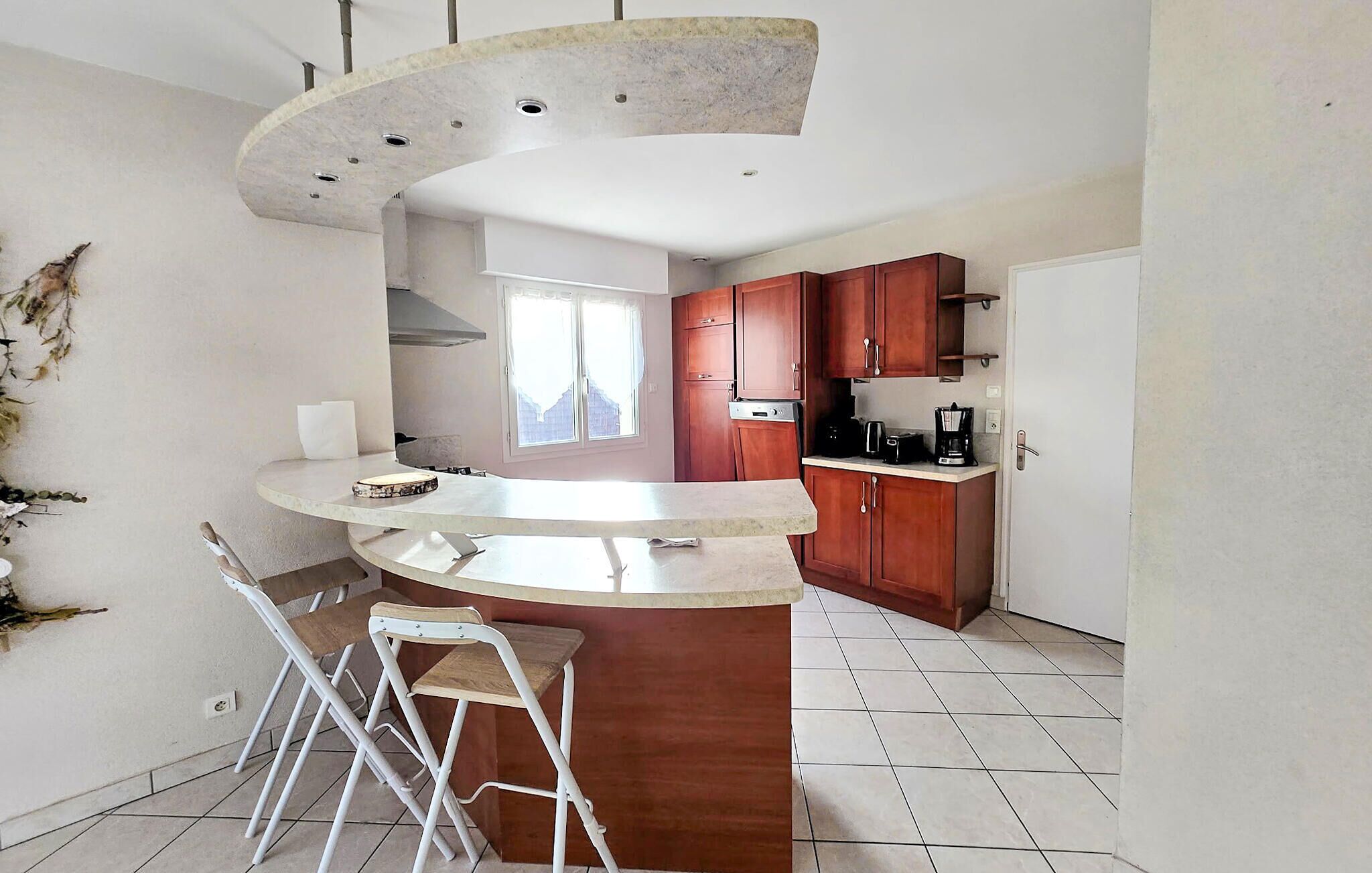 A kitchen with a curved island, wooden cabinets, and a window.