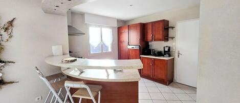 A kitchen with a curved island, wooden cabinets, and a window.