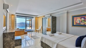 Une chambre d’hôtel moderne avec un grand lit, un bureau et une vue sur la mer.