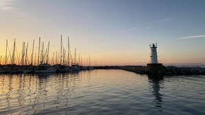 Un port de plaisance où sont amarrés de nombreux voiliers, avec un phare en arrière-plan.