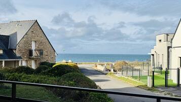 Une route côtière menant à un bâtiment en pierre d’où l’on a une vue sur la mer.