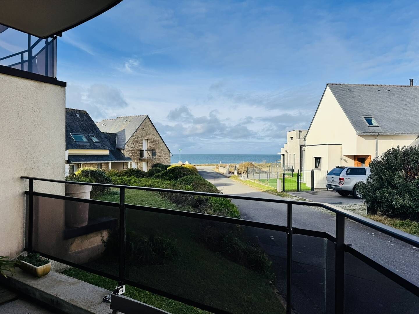 Een woongebied aan de kust met huizen, een weg en uitzicht op zee.