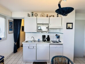 A compact kitchen with white cabinets, a microwave, a coffee maker, and a dishwasher. - Appt 3 pièces, wifi, parking , vue mer partielle (QUIBERON)