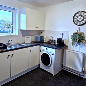 A modern kitchen with a washing machine, a microwave, and a sink.