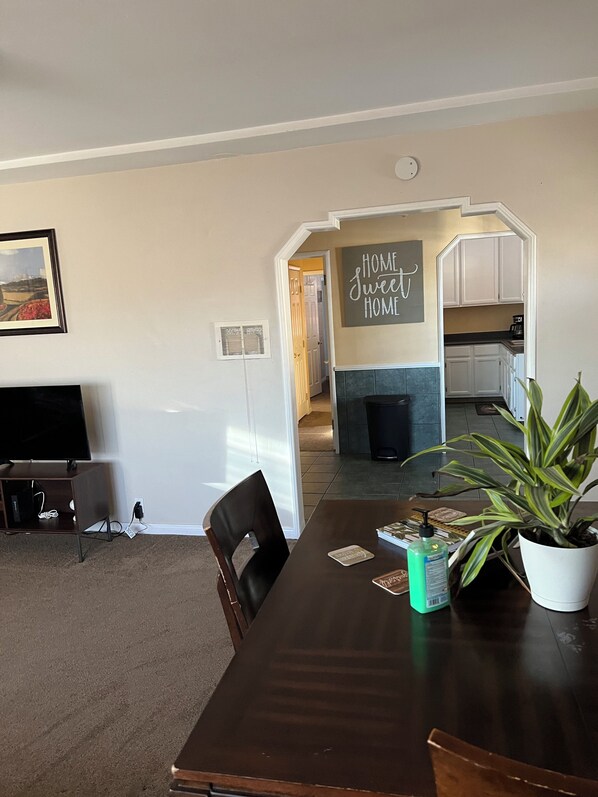 A dining area with a dark wooden table, chairs, a potted plant, and a sign that reads "HOME sweet HOME". - Serene 2-bedroom house with AC and jacuzzi in Signal Hill (Signal Hill)