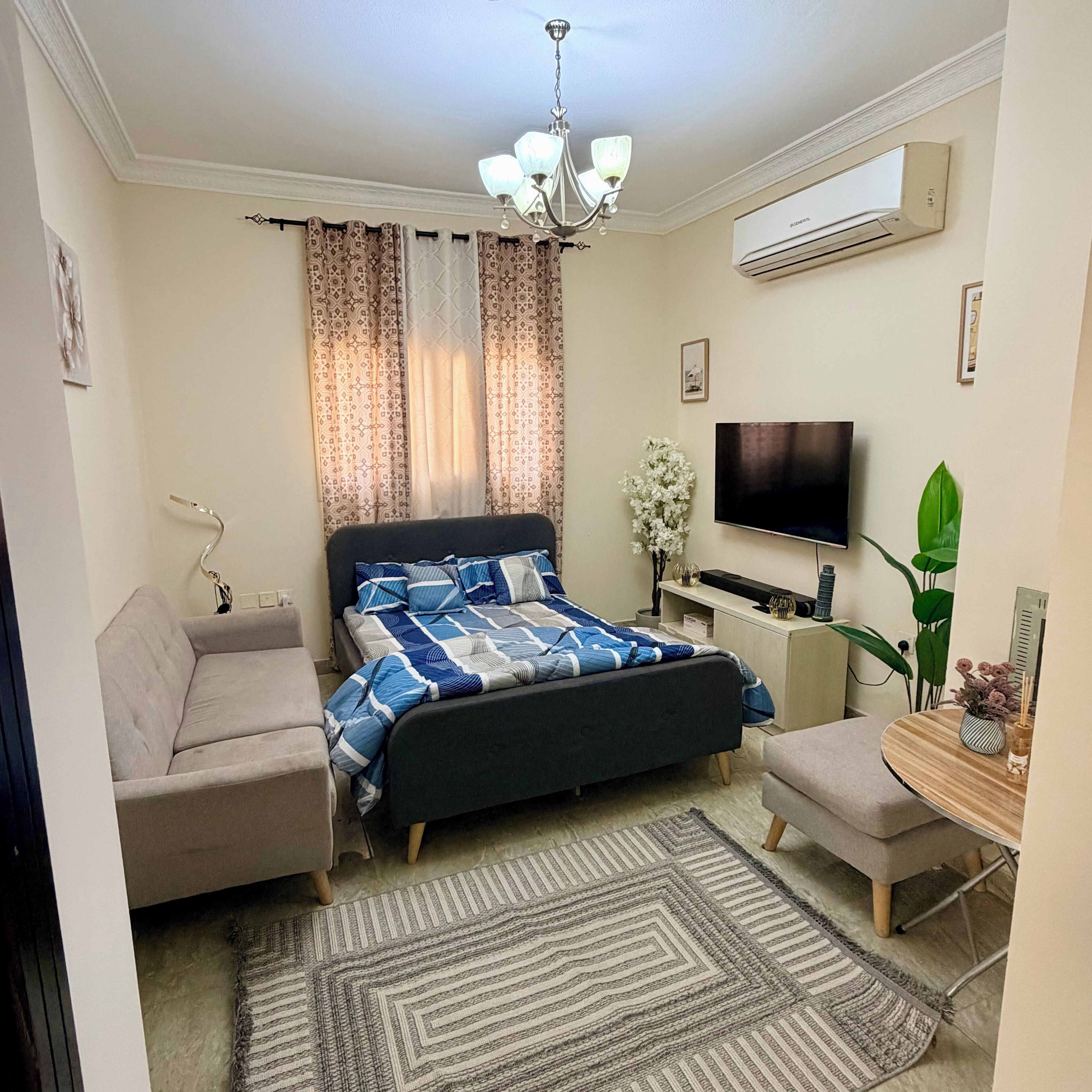 Una camera da letto con un letto, una scrivania, una sedia, una TV e un condizionatore d'aria.