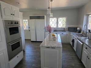 A modern kitchen with white cabinetry, stainless steel appliances, and a marble island. - Spacious 5-bedroom house in Colorado Springs (Colorado Springs)