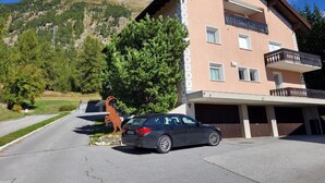 Un edificio de varios pisos con un estacionamiento, una estatua de un caballo y montañas al fondo.