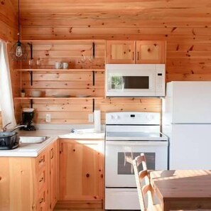 A wooden kitchen with a microwave, stove, and refrigerator.