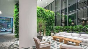 Zona salotto interna moderna con divano, poltrone e tavolino, immersa nel verde e con un pavimento decorato.