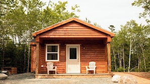 Una petita cabana de fusta amb teulada a dues aigües, dues finestres i una porta. Hi ha dues cadires Adirondack a l'exterior.