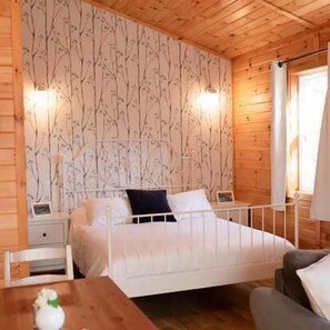 A wooden cabin bedroom with a bed, bedside tables, and a nightstand.