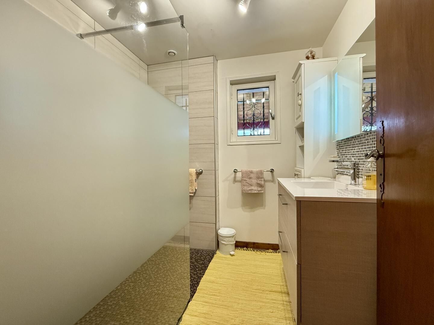 A modern bathroom with a shower, toilet, and sink.