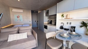 Una cucina moderna con zona pranzo, divano e un piccolo tavolo apparecchiato per due.