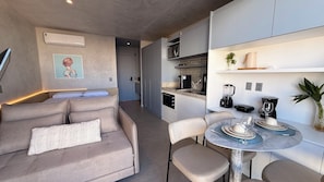 A modern kitchen with a dining area, a sofa, and a small table set for two. - Modern studio apartment, penthouse with incredible views and pool, in Corredor da Vitória. (Salvador)