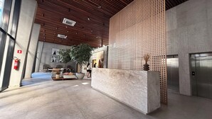 Una hall moderna con reception, area salotto e una grande pianta.