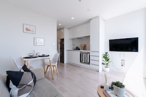 Un appartement moderne doté d’un coin repas, d’une kitchenette et d’un téléviseur fixé au mur.