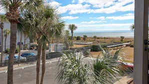 Blick vom Balkon auf einen Strand mit Palmen und einen Parkplatz.