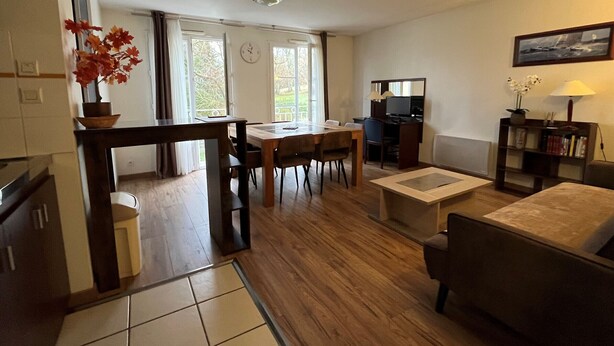 Una sala de estar con un sofá, una mesa de comedor y una zona de cocina con estufa.