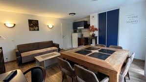 Una sala de estar moderna con una mesa de comedor de madera, un sofá y una zona de cocina al fondo.