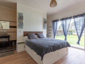 A bedroom with a bed, bedside tables, a mirror, and a view of the outdoors.