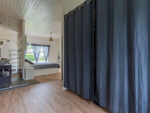 Ein Schlafzimmer mit einem Bett, einem Schreibtisch und einem Fenster mit Vorhängen.