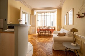 A living room with a dining area, a white sofa, a small table, and a fireplace. - Appartement La Bourdonnais - Welkeys (Paris)