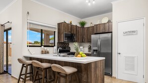 A modern kitchen with a central island, bar stools, a refrigerator, and a microwave. - Tebenki Retreat - Entire House (Boegoeroei)