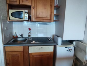 Eine kleine Küche mit Holzausstattung, einer Mikrowelle, einem Toaster und einem Kühlschrank.