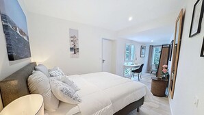 Un dormitorio con cama, escritorio, silla, espejo y puerta.