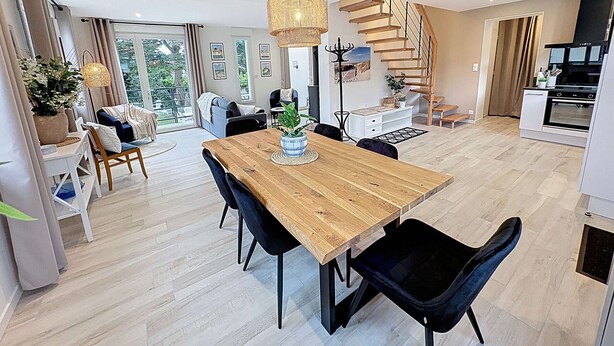 Una cocina moderna con escalera de madera, un comedor con mesa de madera y vistas al exterior.