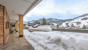 Ett hotell med en träfasad, ett takförsett utomhusområde och utsikt över snötäckta berg.