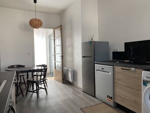 A modern kitchen with a dining area, stainless steel appliances, and a view to the outside. - Cozy Stay in Reims with Parking and Private Terrace (Reims)