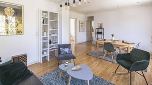 Una sala de estar moderna con comedor, que incluye una estantería, una mesa de centro y una araña.