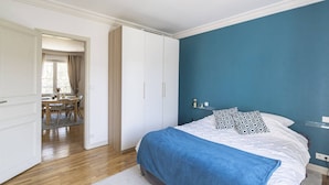 Un dormitorio con una cama, un escritorio y una silla en una zona separada.