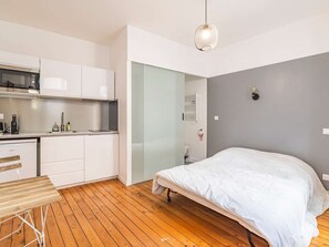 A compact room with a bed, a kitchenette, and a wooden floor. - Spacious Renovated House Near St-Rémi Basilica, 11 Pers, Terrace (Reims)