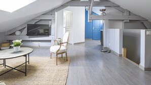 Um apartamento tipo loft moderno, com claraboia, televisão de tela plana, área de refeições com mesa e cadeiras, e uma janela grande.