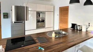 Une cuisine moderne dotée d’appareils électroménagers en acier inoxydable, de plans de travail en bois et de luminaires suspendus.