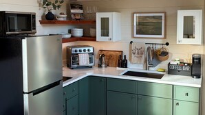 A kitchen with a refrigerator, oven, toaster, sink, and coffee maker. - Green Drake Tiny Home (Pray)