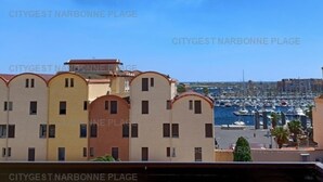 A building with a row of balconies overlooking a marina with boats. - Charming apartment with balcony, pool view - 5 guests (Gruissan)