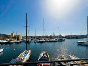 Un puerto deportivo con numerosas embarcaciones amarradas, cielo despejado y edificios al fondo.