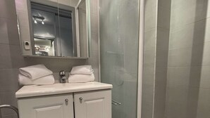 A modern bathroom with a glass-enclosed shower, a white vanity with a mirror, and a toilet.