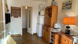 Kompakti keittiö, jossa on jääkaappi, mikroaaltouuni ja puukaapit.