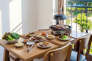 A dining table with a grill, various dishes, and chopsticks. - Samcheok The Ggeullim Pension (Samcheok)